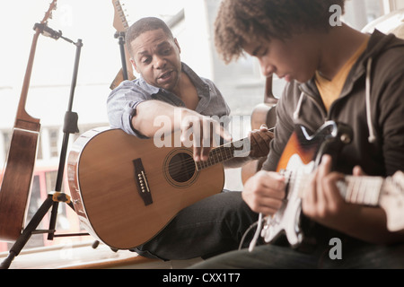 Père expliquant la guitare électrique à l'adolescence Banque D'Images