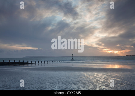 Réflexions sur la plage à West Wittering au coucher du soleil. Banque D'Images