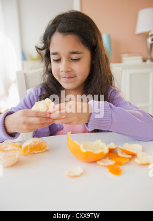 Mixed Race girl peeling une orange Banque D'Images