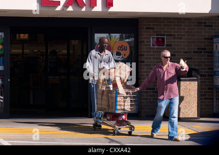 Un homme noir et un homme de race blanche pousser et tirer un panier chargé d'un supermarché à Oklahoma City, Oklahoma, USA. Banque D'Images