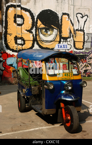 Moteur Tricycle taxi pousse-pousse en avant du mur de graffiti Bangkok, Thaïlande Banque D'Images