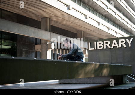 Élève assis en face de la bibliothèque de l'Université d'Edimbourg. Banque D'Images