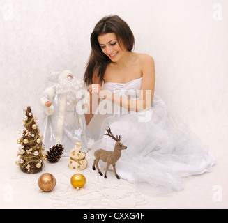 Jeune femme en robe blanche entouré de décorations de Noël Banque D'Images