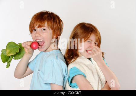 Boy eating radis, fille de rejet de la nourriture crue ou de légumes Banque D'Images