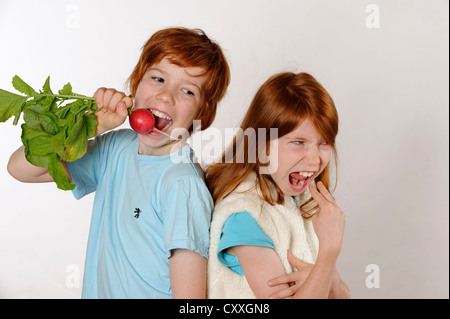 Boy eating radis, fille de rejet de la nourriture crue ou de légumes Banque D'Images