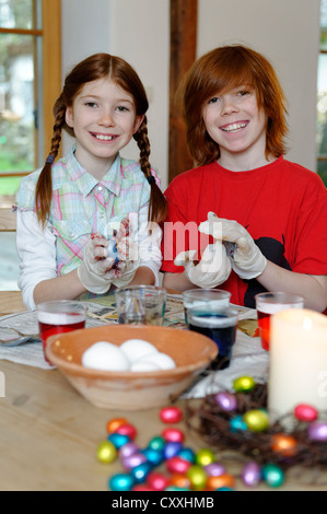 Garçon et fille d'oeufs de Pâques à colorier, peindre des oeufs de Pâques Banque D'Images