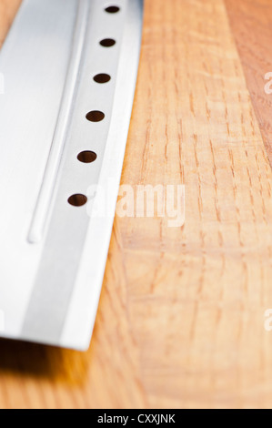 Le couteau avec les trous allongés sur une planche à découper en bois Banque D'Images