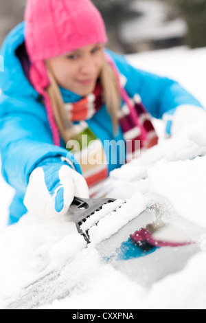 Woman brushing la neige des pare-brise de voiture travail essuyage racloir d'hiver Banque D'Images