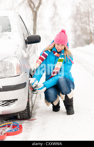 Woman putting winter de chaînes sur roue voiture ventilation neige Banque D'Images