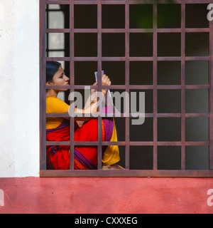 Jeune femme tenant une feuille de papier assise sur le bord d'une fenêtre Bar à Dakshinachitra Dance Centre, Chennai, Inde Banque D'Images