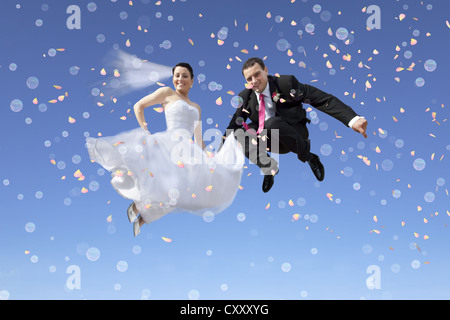 Mariés, couples nuptiales en saut à l'air, contre un ciel bleu, des bulles, des confettis Banque D'Images