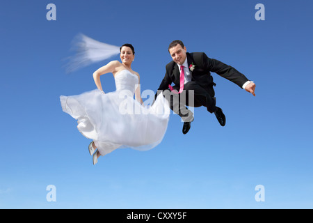 Mariés, couples nuptiales de sauter dans l'air, contre un ciel bleu Banque D'Images