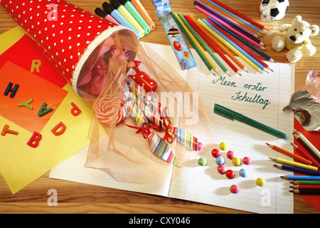 Schultuete ou cône scolaire rempli de cadeaux et de bonbons à côté de crayons de couleur et un ordinateur portable avec le titre Mein erster Banque D'Images