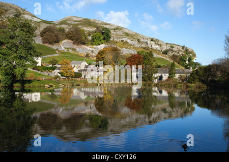 Réflexions au bord de l'eau du crag de Kilnsey, maisons et couleurs des feuilles d'automne dans le lac de pêche à la truite, Wharfedale, Yorkshire Dales, Royaume-Uni. Banque D'Images