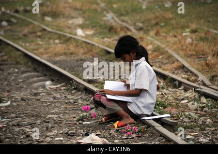 Fille cambodgienne l'apprentissage avec un livre, assis sur une ancienne voie de chemin de fer, Battambang, Cambodge, Asie Banque D'Images