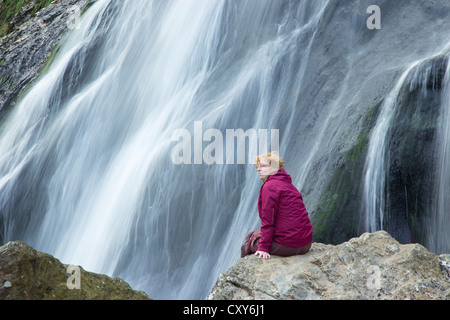 Femme assise en face de Powerscourt Waterfall, comté de Wicklow, Irlande Banque D'Images