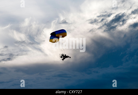 Parapente powered volant sous les nuages menaçants tourbillonnant Banque D'Images