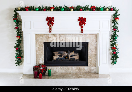 Foyer à gaz naturel décoré avec des ornements de Noël, bougies et panier de pommes de pin séché pour la saison de vacances Banque D'Images