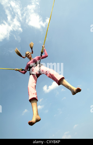 Jeune femme sautant avec les cordes d'une trampoline bungee Banque D'Images