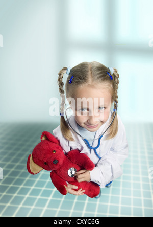 Jeune fille à l'écoute de son nounours avec le battement d'un stéthoscope, images symboliques pour les aspirations de carrière, médecin Banque D'Images