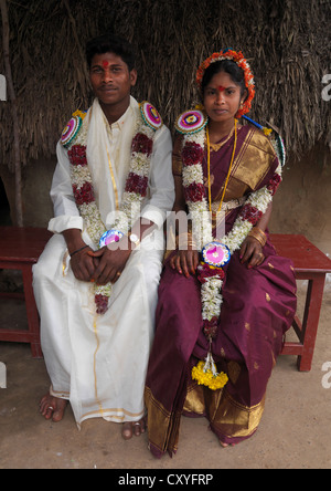 Les jeunes mariés assis sur une banque habillé pour la cérémonie et ornées de guirlandes de fleurs, Pondicherry, India Banque D'Images