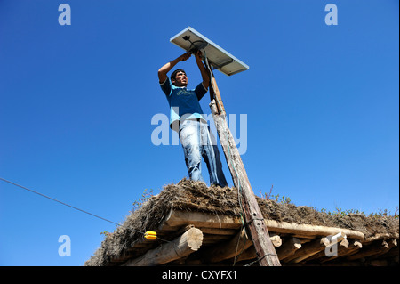 Jeune homme mountain cellules solaires sur le toit d'une simple hutte d'un petit exploitant agricole, du Gran Chaco, Santiago del Estero Province Banque D'Images