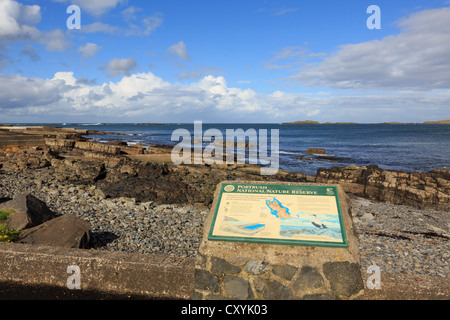 La zone côtière information board à propos de rocky shore de la réserve naturelle nationale marine inhabituelle avec des pierres à Portrush Irlande Banque D'Images