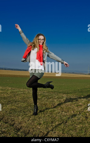 Jeune femme, 25 ans, portant un foulard rouge dans un champ ouvert Banque D'Images