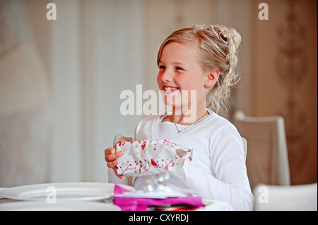 Fille, 9 ans, unwrapping gift sur sa Première Communion jour, région de Münster, Rhénanie du Nord-Westphalie Banque D'Images