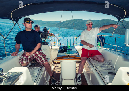 Trois hommes d'équipage d'un bateau à voile à l'arrière d'un yacht au large de la côte croate, Croatie, Europe Banque D'Images