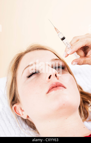 Seringue en face de la face d'un patient, traitement Botox Banque D'Images