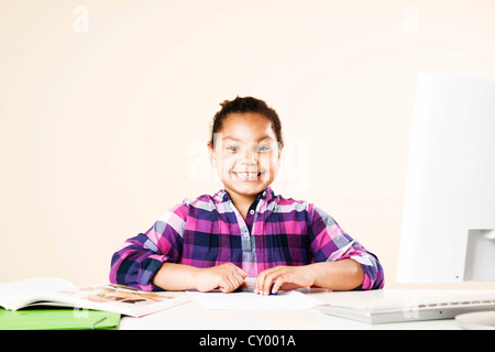 Smiling girl sitting at a desk Banque D'Images