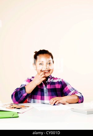 Smiling girl sitting at a desk Banque D'Images