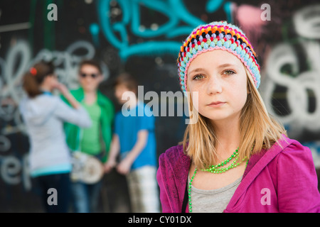 Les adolescents debout devant un mur de graffiti, une fille debout dans l'avant-plan Banque D'Images