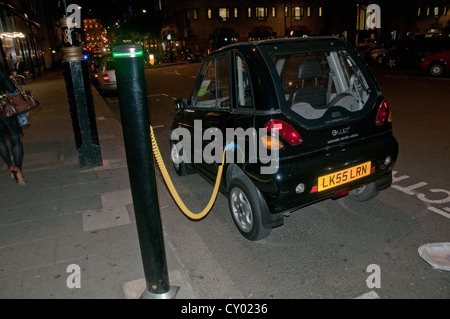 Une voiture électrique G-Wiz sur frais dans le centre de Londres la nuit Banque D'Images