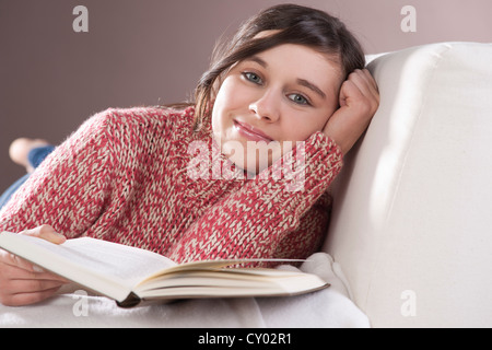 Girl relaxing sur un canapé avec un livre Banque D'Images