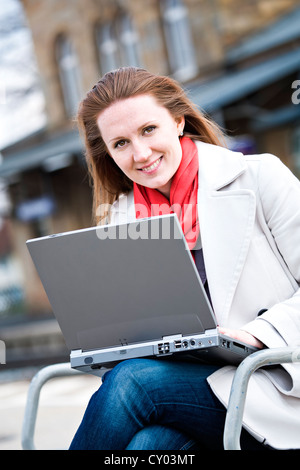 Young woman with laptop à rail station Banque D'Images