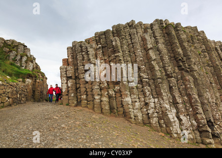 Les gens qui marchent à travers la porte du géant entre colonnes verticales de basalte (roche de lave formant le Giant's Causeway, l'Irlande du Nord Banque D'Images