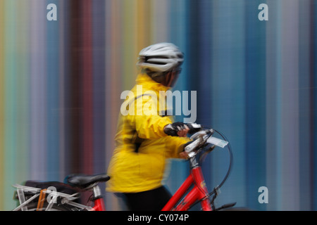 Une femelle avec le vélo touristique passant le Tour Moretti à l'Esplanade du général de Gaulle à la défense, Paris Banque D'Images