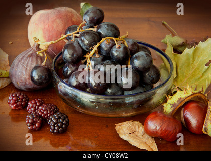 Assortiment de fruits d'automne:dans un bol les raisins, figues, mûres, pêches et châtaignes Banque D'Images