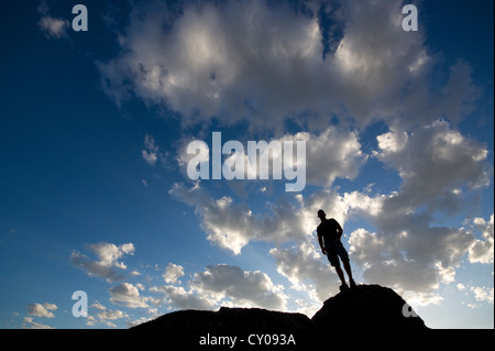 Silhouette de figure masculine debout sur rock against blue sky Banque D'Images