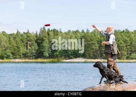 L'homme entraîner son retriever en jetant un mannequin Banque D'Images