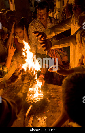 Les fidèles hindous passent leurs mains à travers un rituel sacré flamme à Co. ghat, Mathura, Inde Banque D'Images