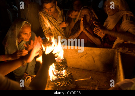 Les fidèles hindous passent leurs mains à travers un rituel sacré flamme à Co. ghat, Mathura, Inde Banque D'Images