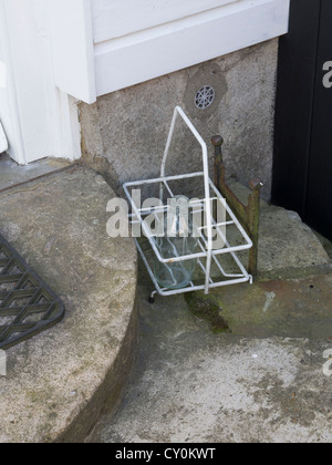 Bouteille de lait vide en attente sur une porte. Banque D'Images