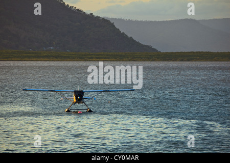 Le soleil brille sur le côté de l'hydravion amarré dans le port de Cairns, Queensland, Australie, avec décor de montagnes au lever du soleil Banque D'Images