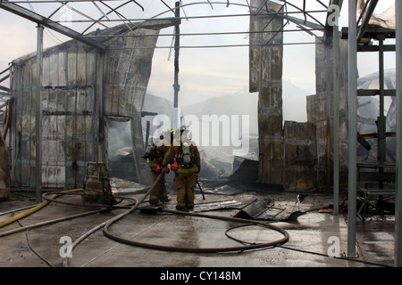 Deux pompiers sur les lieux d'un incendie industriel Banque D'Images