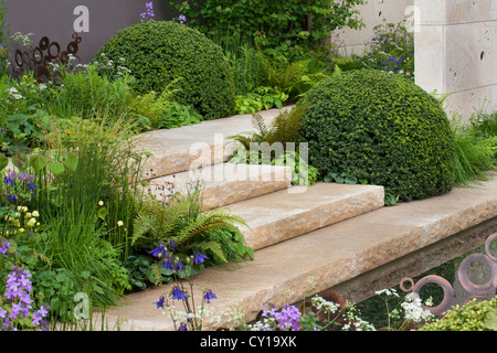 Jardin contemporain conçu avec des arbustes et de l'eau en forme de fonction. M & G le jardin. Design : Andy Sturgeon Banque D'Images