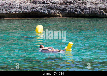 Femme de soleil sur matelas d'air flottant sur l'eau de mer Espagne Iles Baléares Majorque Mer Méditerranée Banque D'Images