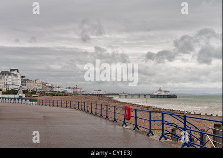 Ciel couvert et orageux à jour de pluie avec Eastbourne pier et promenade côtière humide mer sentier jusqu'churners avec breakers côte sud Banque D'Images